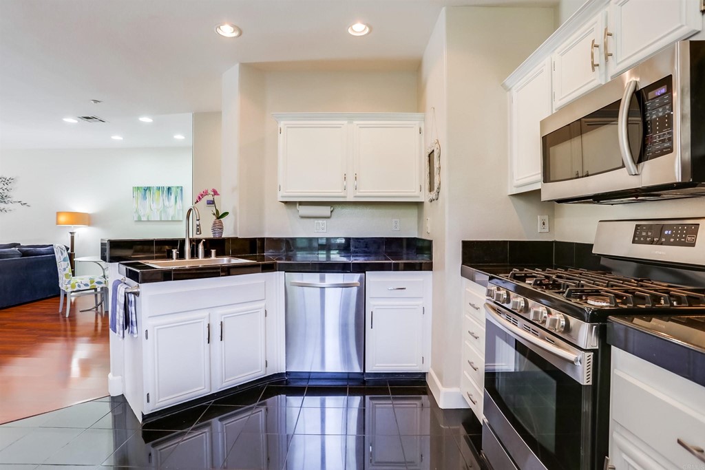 6094 Citracado Circle Carlsbad, CA 92009 - Photo 10 of 28 a kitchen with stainless steel appliances a sink a stove top oven a counter space and cabinets