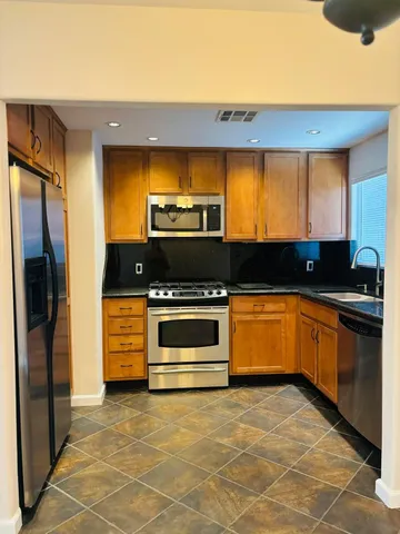 a kitchen with granite countertop a stove a refrigerator and a sink