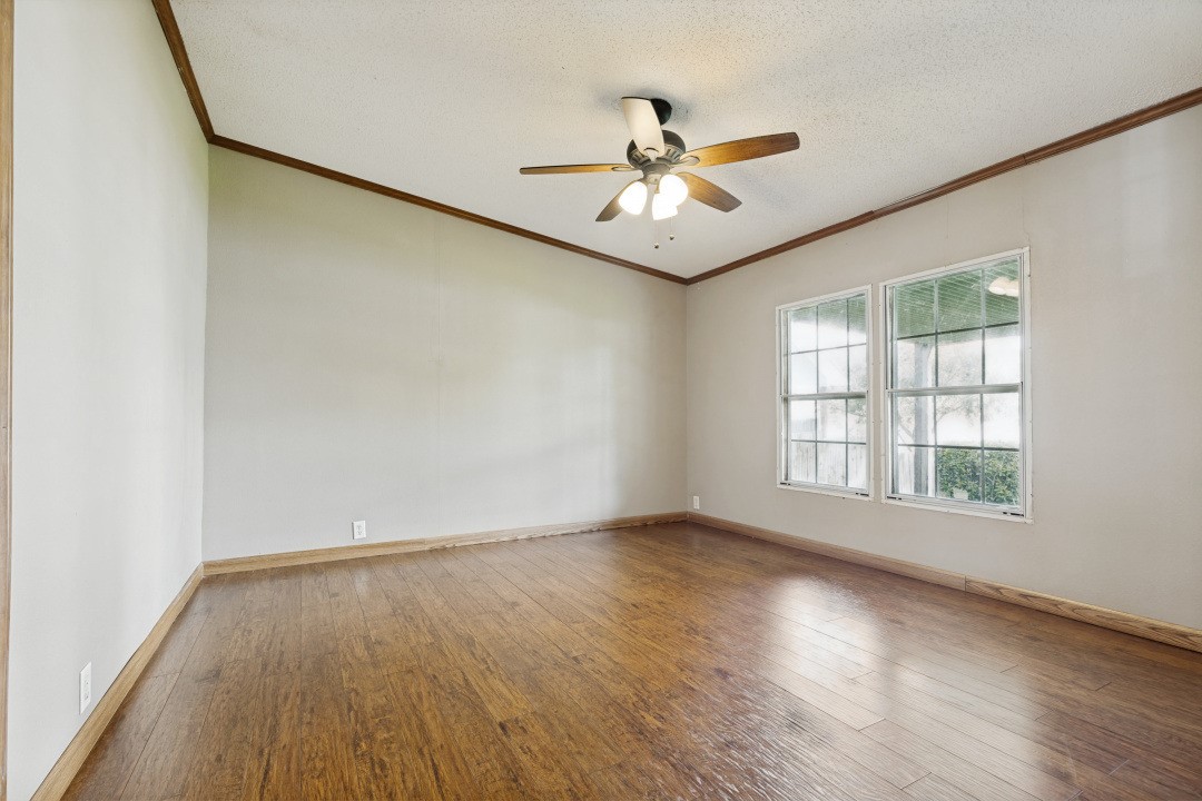 207 Vivian Road Onalaska, TX 77360 - Photo 19 of 34 an empty room with wooden floor fan and windows