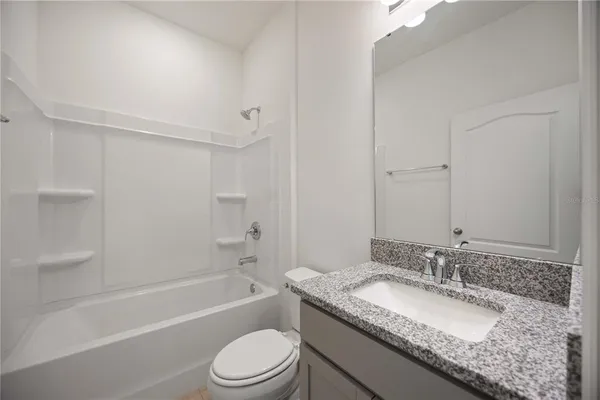 a bathroom with a granite countertop sink a toilet and bathtub