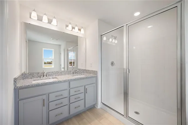 a bathroom with a granite countertop sink mirror and a shower