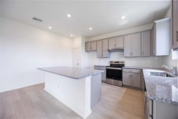 a kitchen with stainless steel appliances granite countertop a sink stove and cabinets