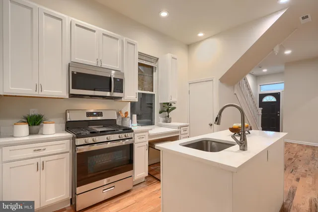 a kitchen with stainless steel appliances granite countertop a stove a sink and a microwave