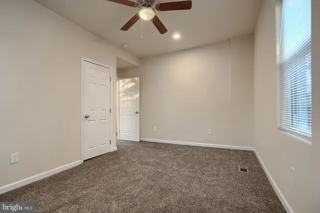 an empty room with a ceiling fan and window