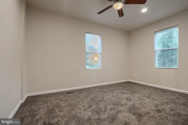 an empty room with a window and a ceiling fan