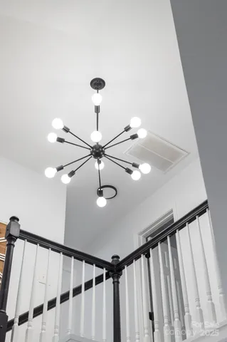 a view of staircase with railing and pendant lights