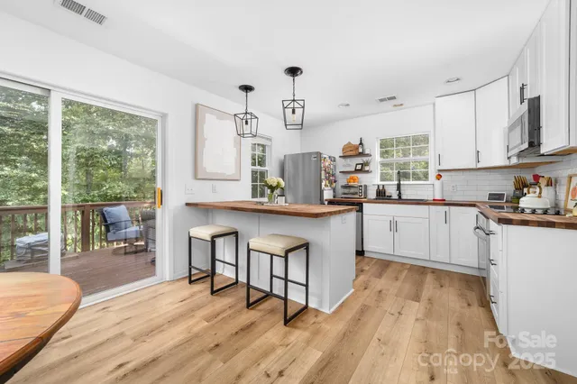 a kitchen with stainless steel appliances granite countertop a kitchen island hardwood floor sink stove dining table and chairs