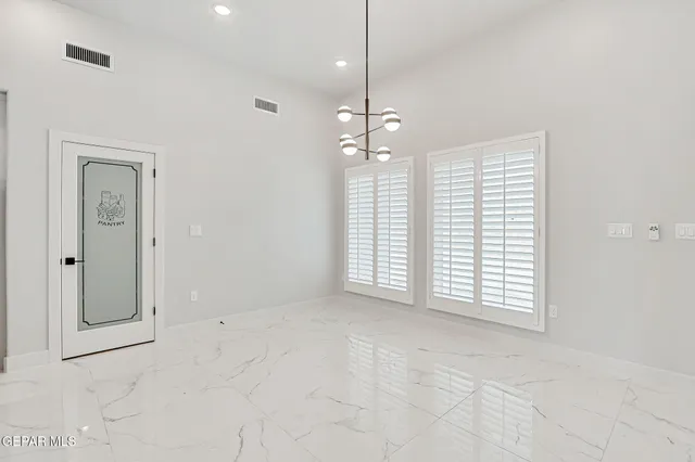 an empty room with chandelier fan and windows