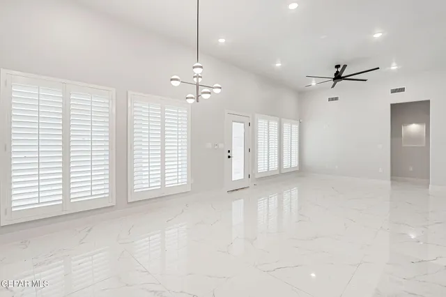 an empty room with windows and ceiling fan