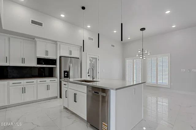 a kitchen with stainless steel appliances kitchen island granite countertop a sink and a refrigerator