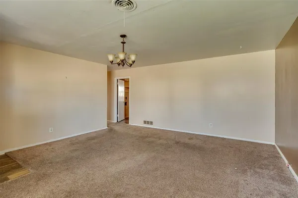 an empty room with windows and chandelier fan