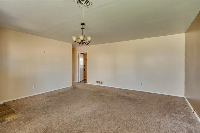 an empty room with windows and chandelier fan