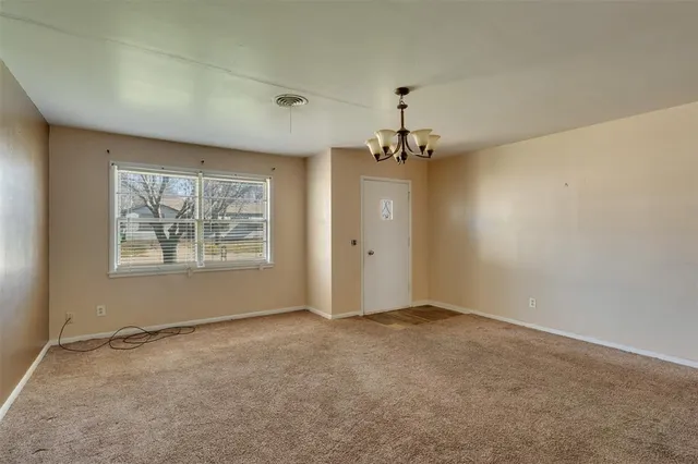 an empty room with a chandelier fan and wooden floor