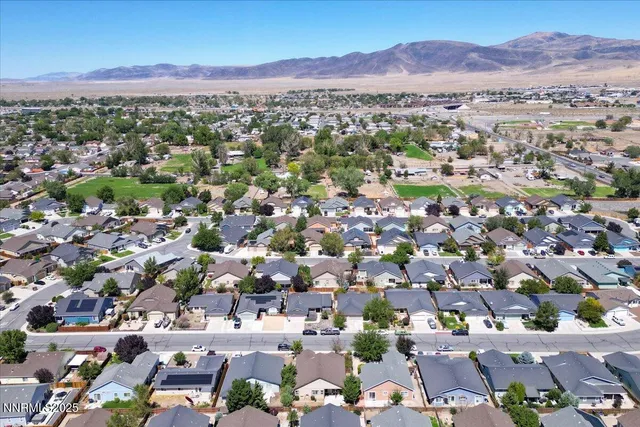 an aerial view of a city with lots of residential buildings and mountain view in back