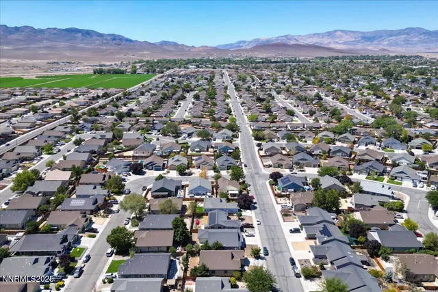 an aerial view of a city with lots of residential buildings and mountain view in back