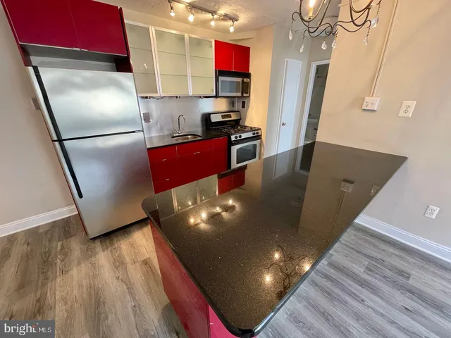 a kitchen with stainless steel appliances granite countertop a refrigerator a stove and a wooden floors