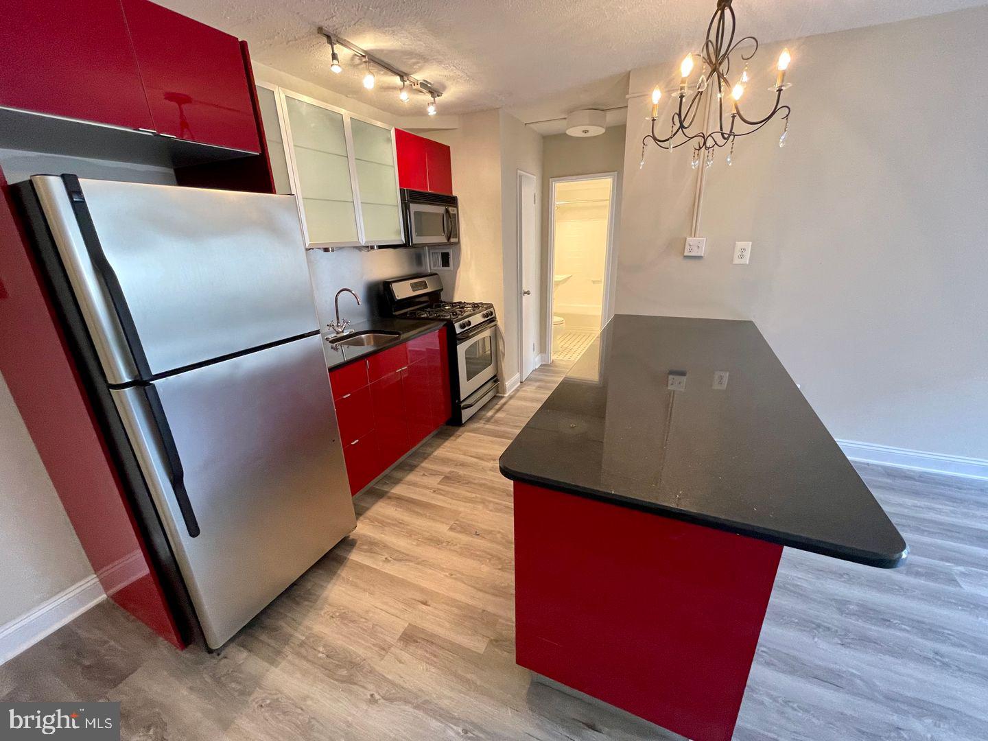 2101-17 Chestnut Street, Unit 1419 Philadelphia, PA 19103 - Photo 5 of 9 a kitchen with stainless steel appliances granite countertop a refrigerator a sink a stove and a wooden floors
