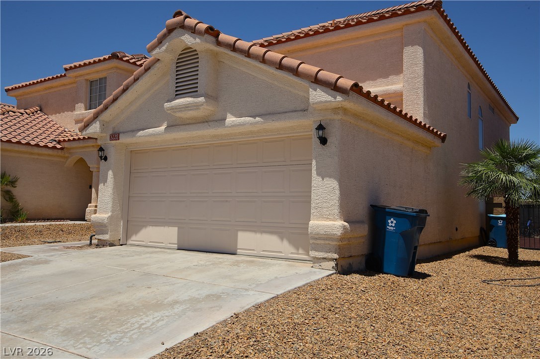8220 Maplestar Road Las Vegas, NV 89128 - Photo 3 of 29 A terracotta-tiled roof crowns this residence, featuring a two-car garage and a paved driveway.