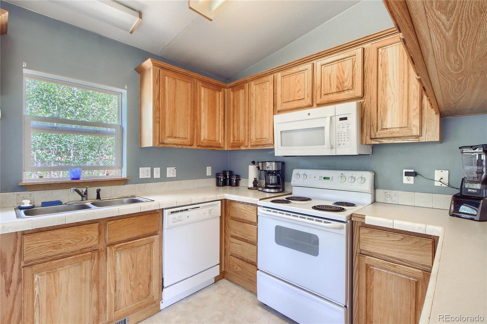 399 Buffum Street Bailey, CO 80421 - Photo 11 of 30 a kitchen with white cabinets appliances a sink and a large window