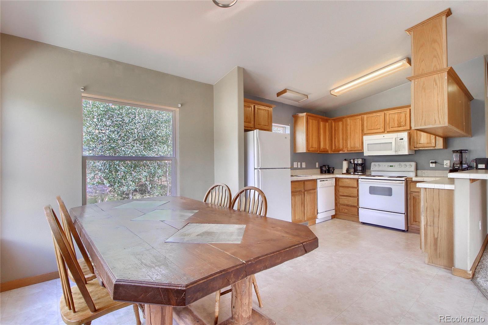 399 Buffum Street Bailey, CO 80421 - Photo 13 of 30 a kitchen with a table chairs a sink dishwasher window and cabinets