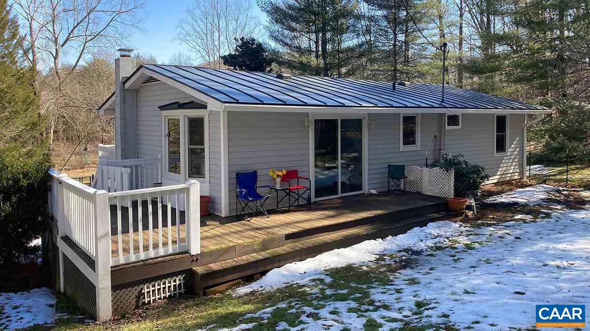 a view of a house with a wooden deck and furniture