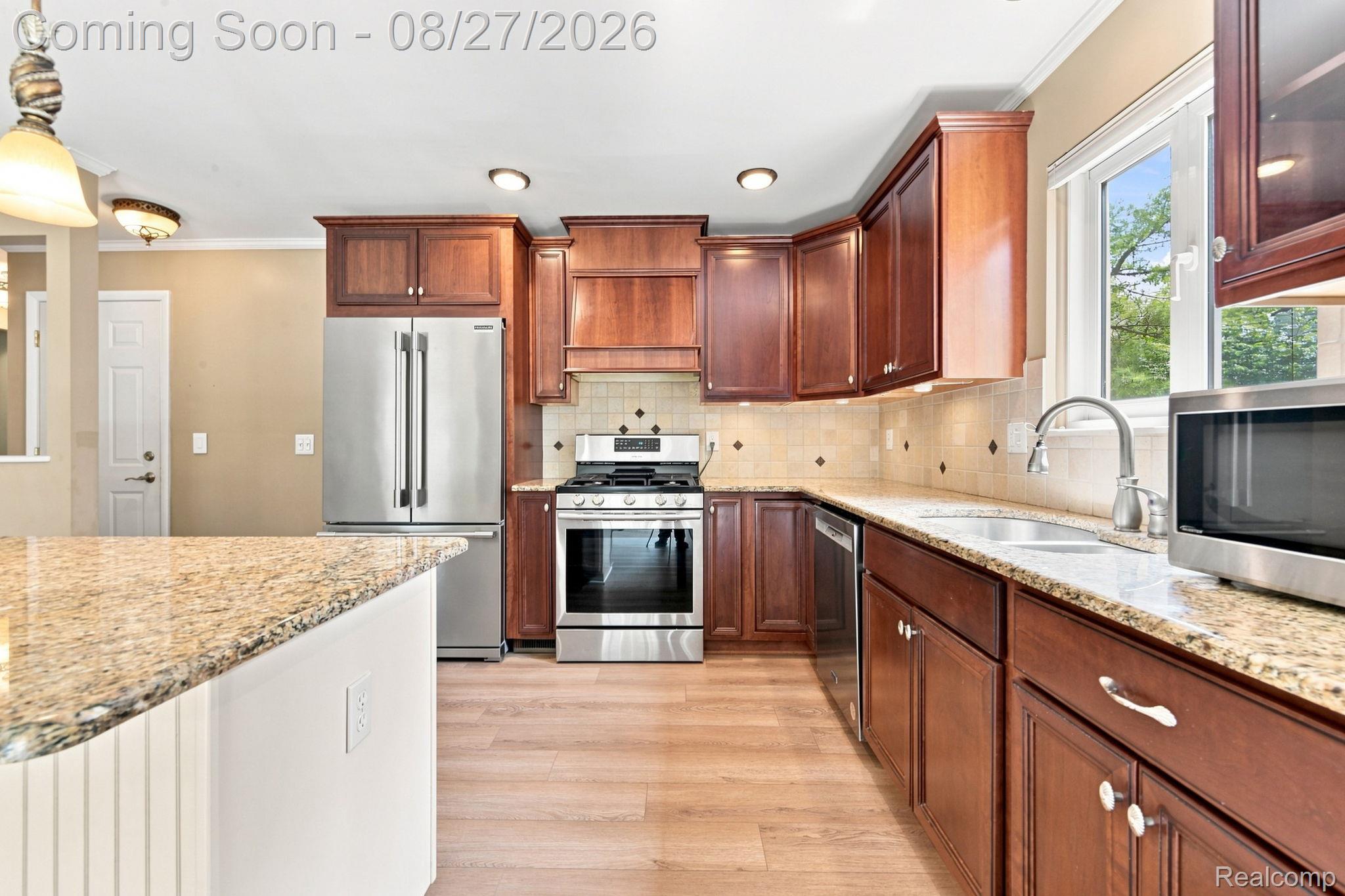 42120 Ridge Road West Novi, MI 48375 - Photo 17 of 32 Kitchen featuring wood-finish flooring, rich wood cabinetry, stainless steel appliances, speckled stone countertops, and a tile backsplash
