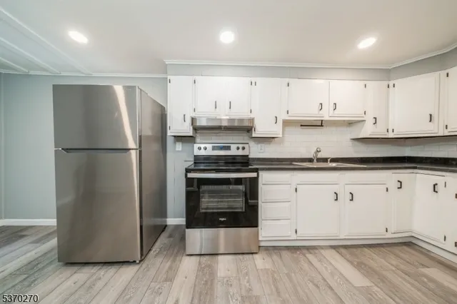 a kitchen with a refrigerator and white cabinets