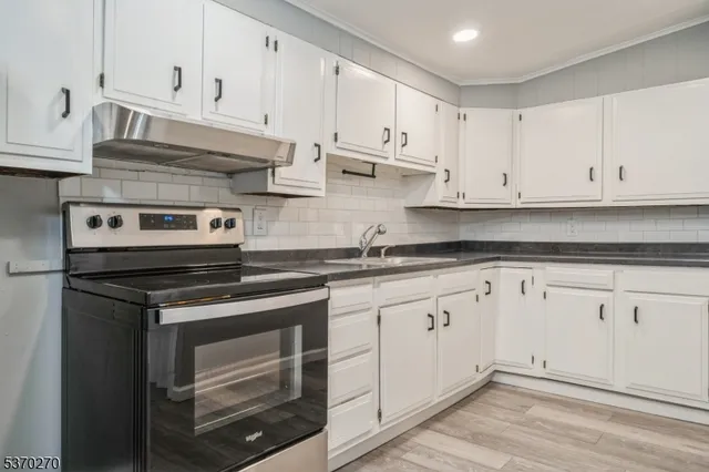 a kitchen with granite countertop white cabinets and stainless steel appliances