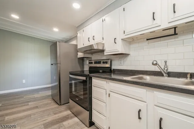 a kitchen with stainless steel appliances granite countertop a sink a stove and cabinets