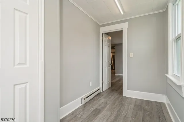 a view of hallway with window and wooden floor