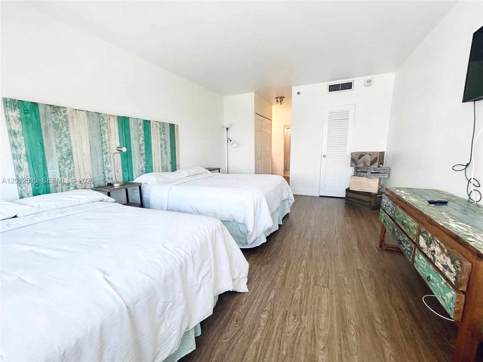 100 Lincoln Road, Unit 922 Miami Beach, FL 33139 - Photo 4 of 9 a bedroom with two beds and a dresser next to a window