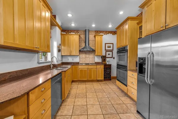a large kitchen with stainless steel appliances kitchen island granite countertop a sink counter space cabinets and a large window