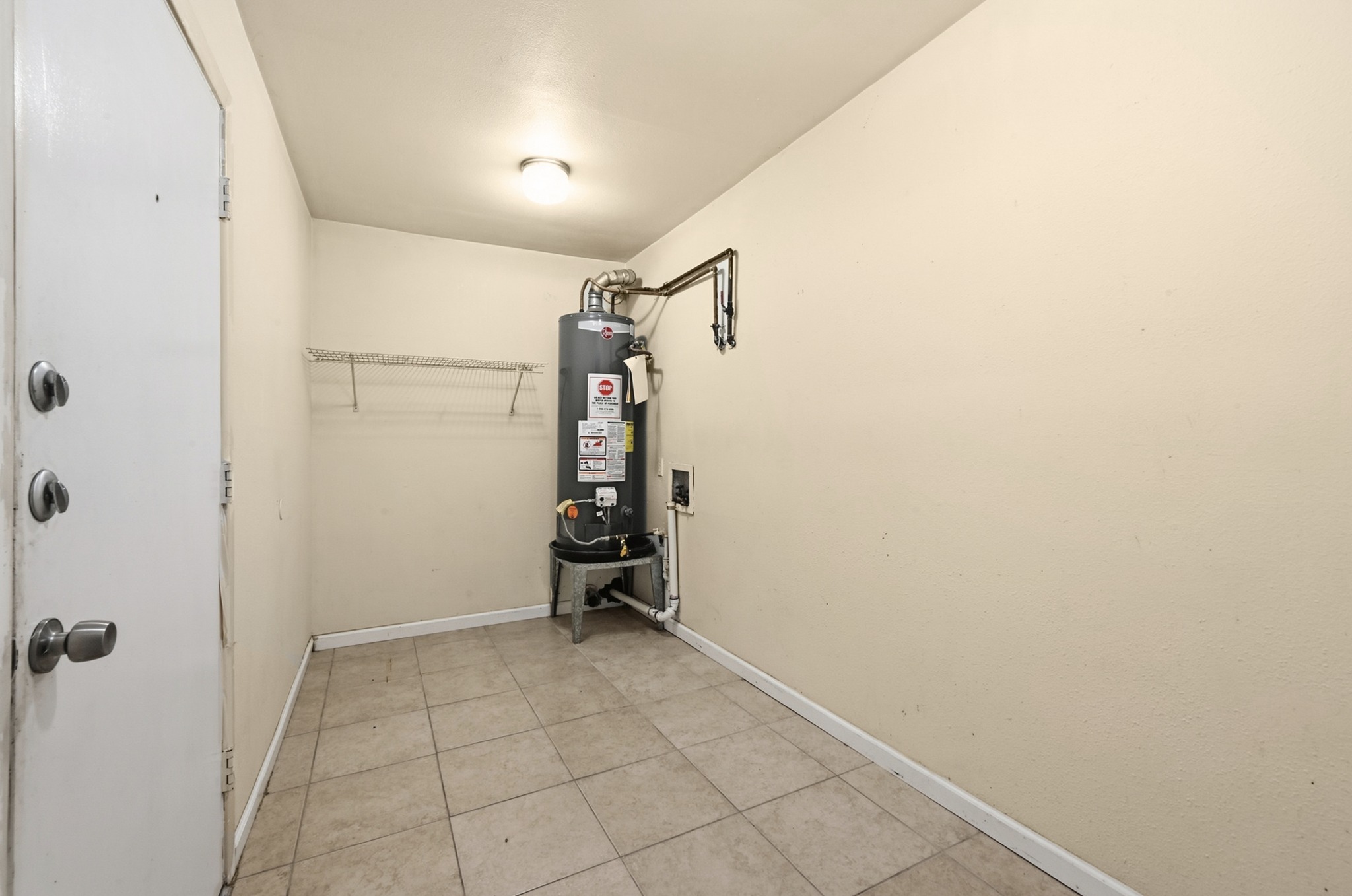 807 Castle Ridge Road, Unit C Austin, TX 78746 - Photo 17 of 26 A functional utility space features durable tiled flooring and a dedicated water heater installation.
