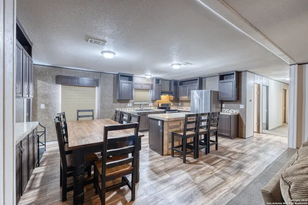 a kitchen with a dining table chairs and refrigerator