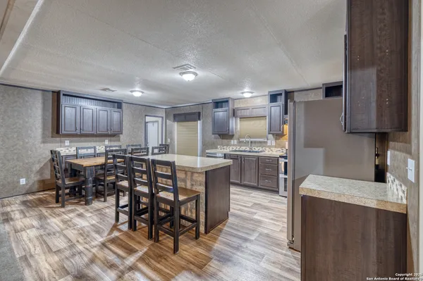 a kitchen with kitchen island granite countertop wooden floors a center island stainless steel appliances and cabinets