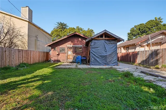 a view of a small house with a small yard and wooden fence
