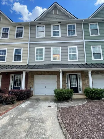 a front view of a house with yard and parking