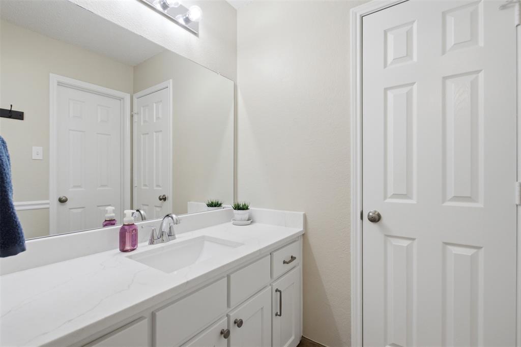 4218 Glistening Spring Rowlett, TX 75088 - Photo 31 of 39 Bathroom vanity featuring a quartz-finish countertop, integrated sink, and chrome fixtures