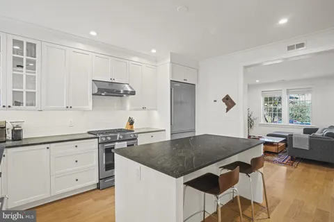 a kitchen with granite countertop a stove a sink a dining table and chairs