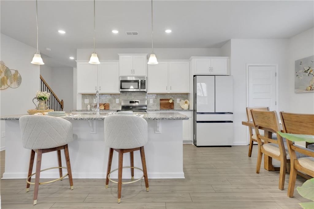 803 Dundee Way Cartersville, GA 30121 - Photo 14 of 37 a kitchen with kitchen island stainless steel appliances a dining table chairs sink and white cabinets