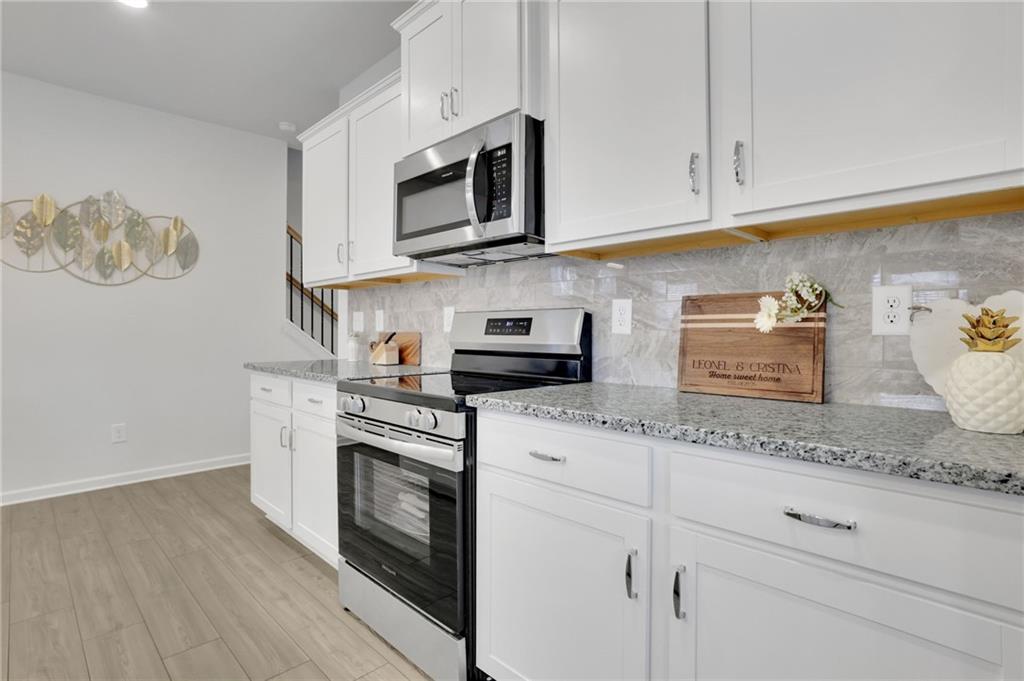 803 Dundee Way Cartersville, GA 30121 - Photo 10 of 37 a kitchen with granite countertop white cabinets stainless steel appliances and wooden floor