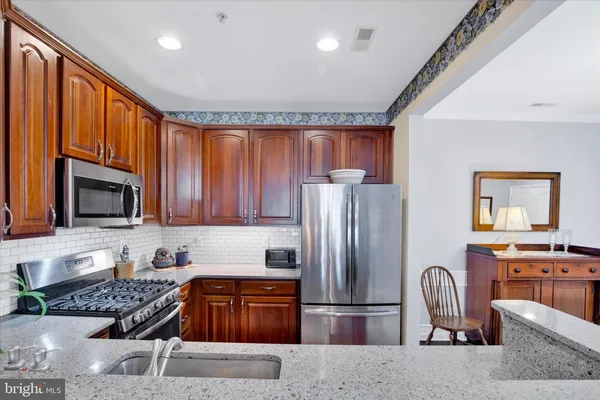 a kitchen with granite countertop a refrigerator and a stove top oven