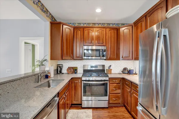 a kitchen with stainless steel appliances granite countertop a refrigerator a sink dishwasher stove and oven