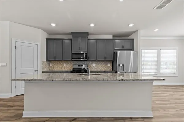 a kitchen with kitchen island granite countertop a stove a sink and white cabinets