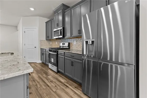 a kitchen with stainless steel appliances granite countertop a refrigerator a sink and wooden cabinets