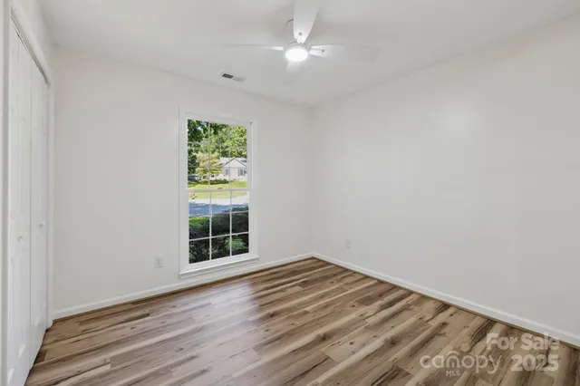 a view of a room with wooden floor and a ceiling fan