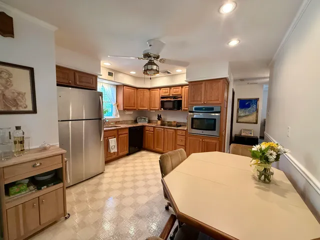 a kitchen with stainless steel appliances a refrigerator a stove a sink dishwasher a dining table and chairs with wooden floor