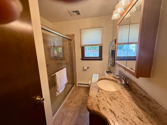 a bathroom with sink granite countertop tub shower and a mirror