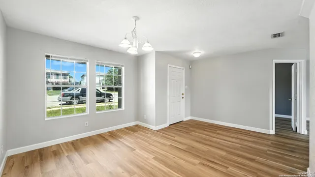 a view of empty room with wooden floor and fan