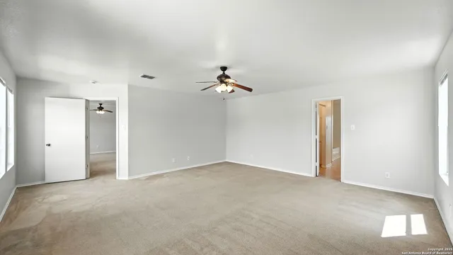 an empty room with a ceiling fan and window